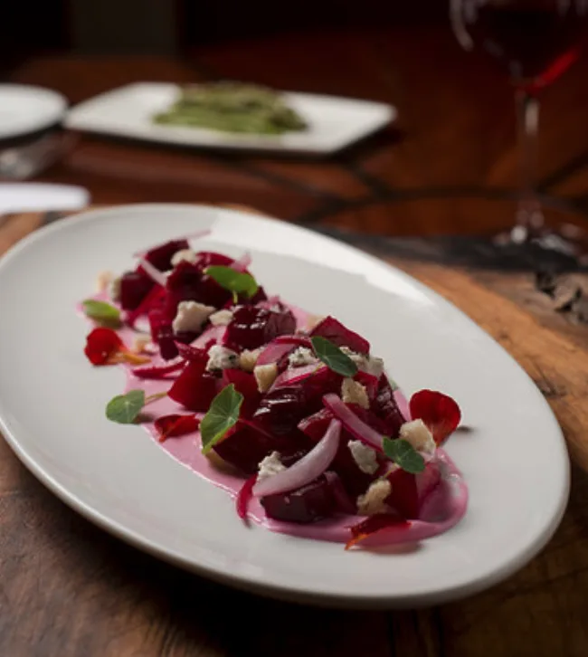 Plated beet salad with cheese, herbs and pickled onion by The Restaurant