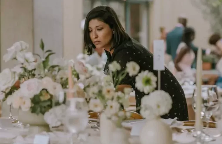 ZUMO event professional inspecting a white floral reception tablescape