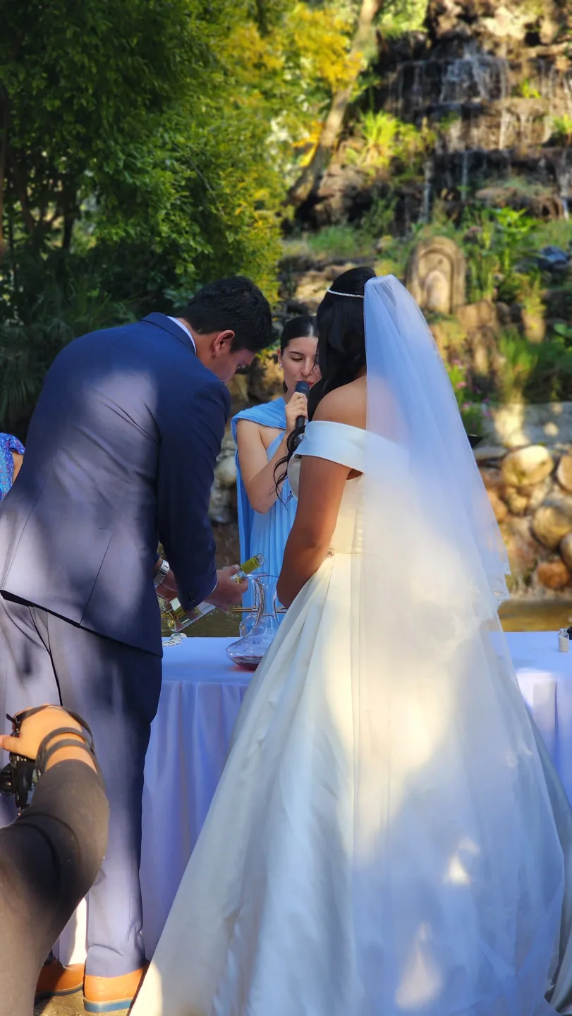Officiant guiding a symbolic wedding beside a garden waterfall