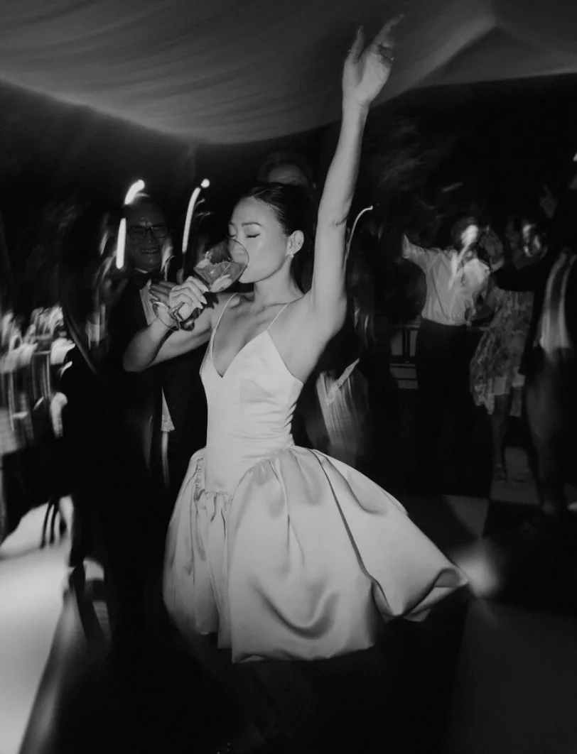 Black-and-white candid photograph of a bride celebrating on the dance floor