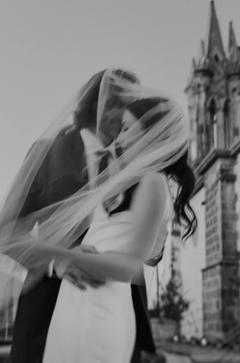 Black-and-white editorial portrait of newlyweds beneath a flowing veil in San Miguel de Allende