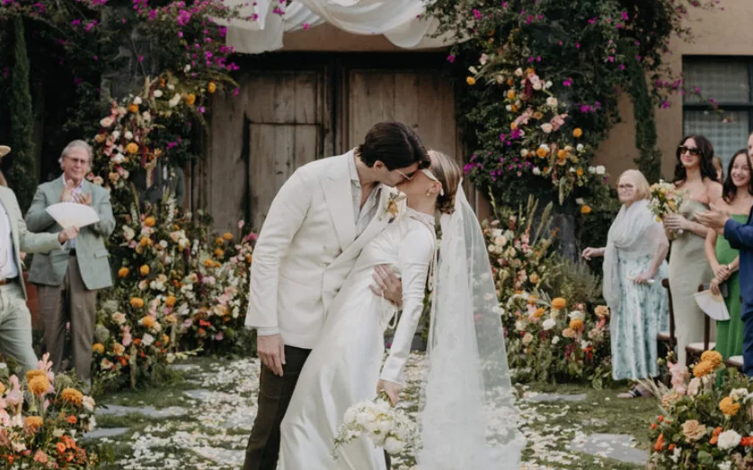Newlyweds kissing beneath a colorful garden ceremony arch