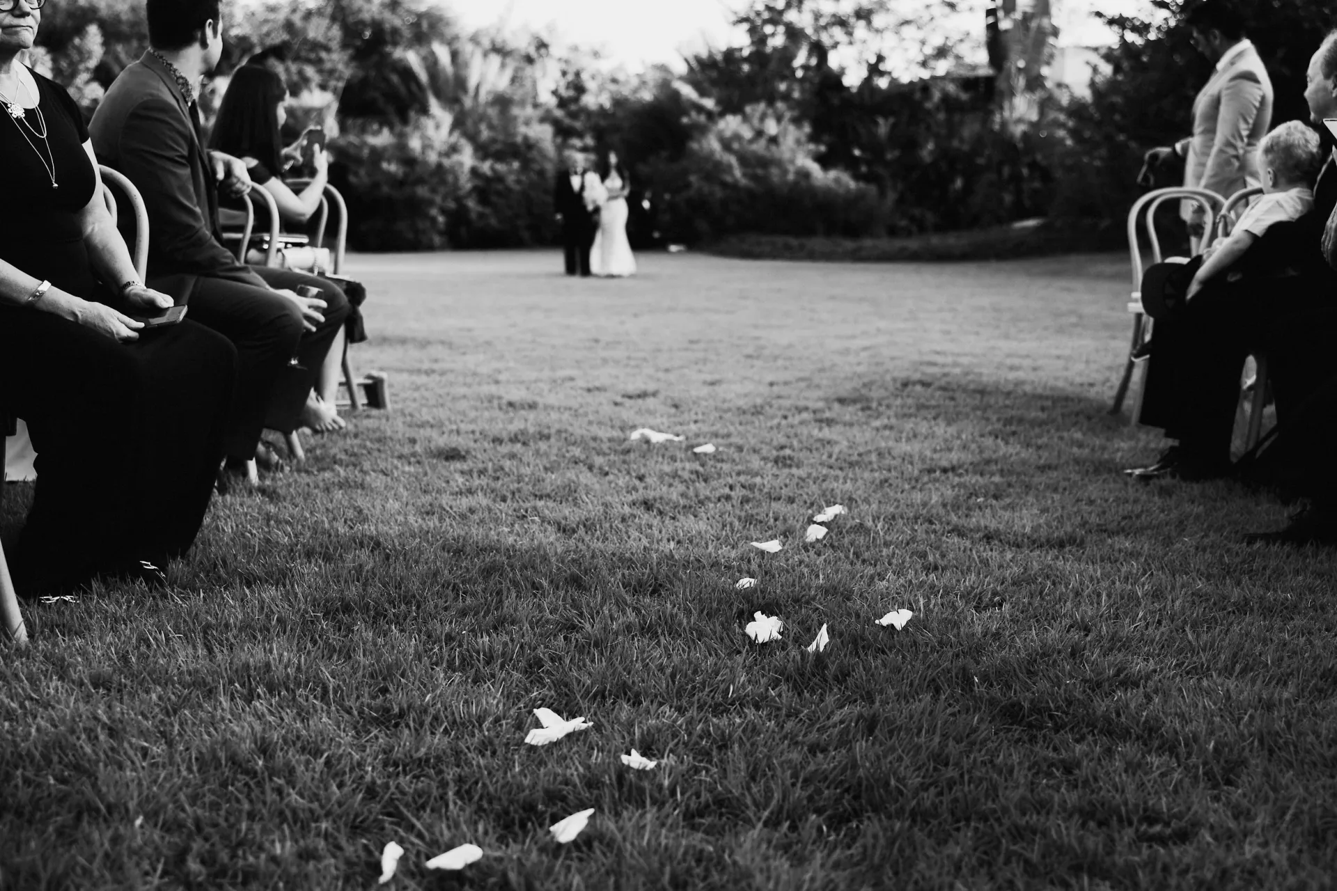 Black-and-white aisle moment with falling petals