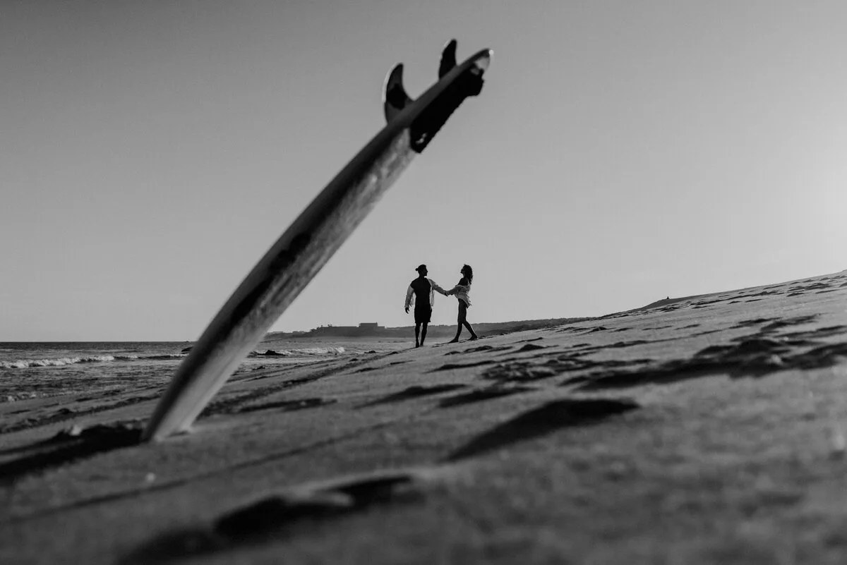 Playful destination couple portrait with a surfboard