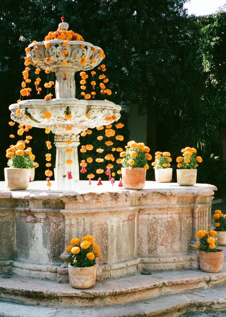 Historic stone fountain decorated with marigolds for a San Miguel wedding