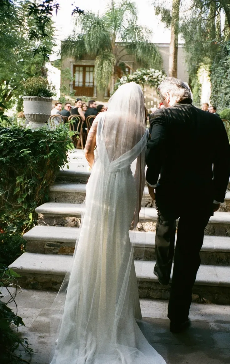 Bride walking with her father toward an intimate garden ceremony