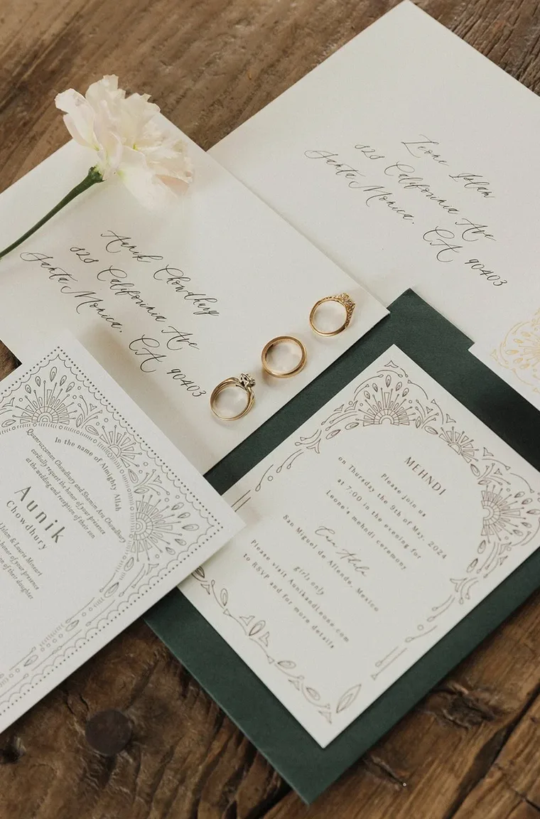 Wedding invitation suite, handwritten envelopes and rings arranged on wood