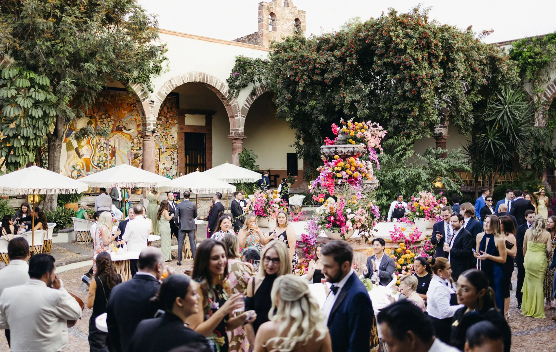 Guests gathering around a flower-covered fountain at a courtyard cocktail reception