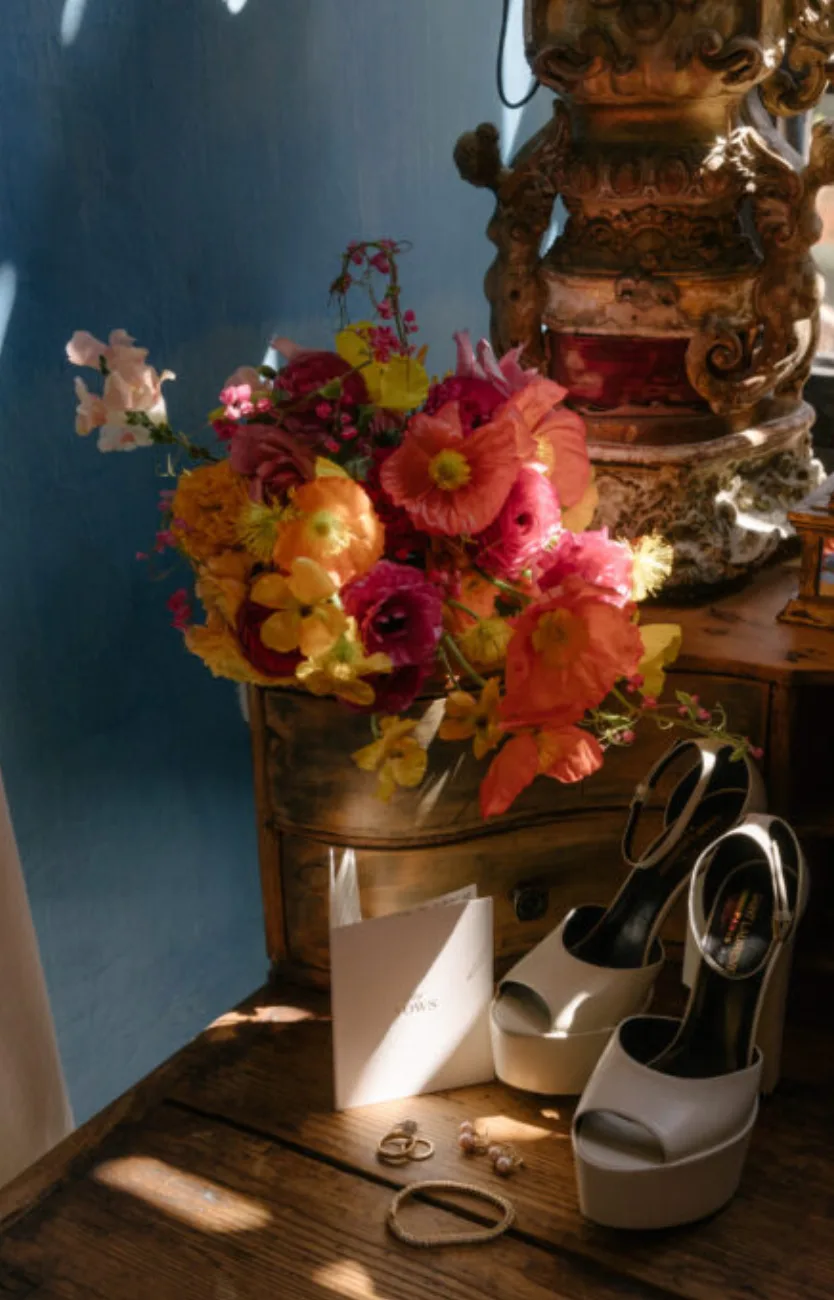 Bridal shoes, jewelry and a vivid bouquet arranged in a historic interior