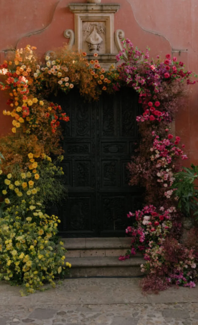 Colonial doorway framed by an abundant multicolored floral installation