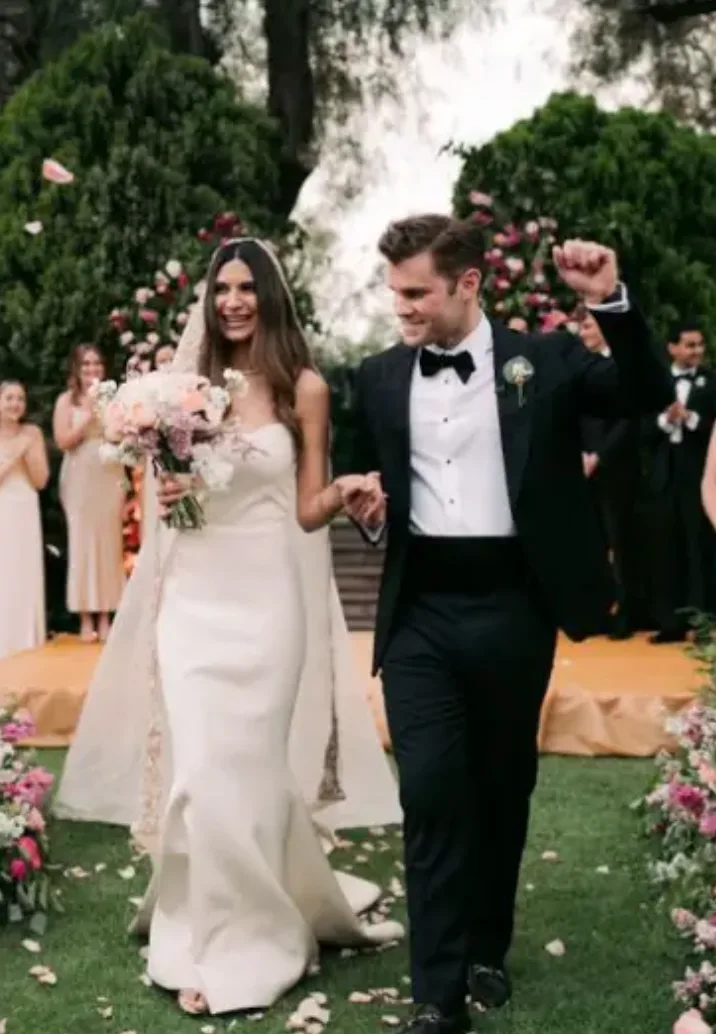 Newlyweds celebrating as they walk from a flower-lined garden ceremony