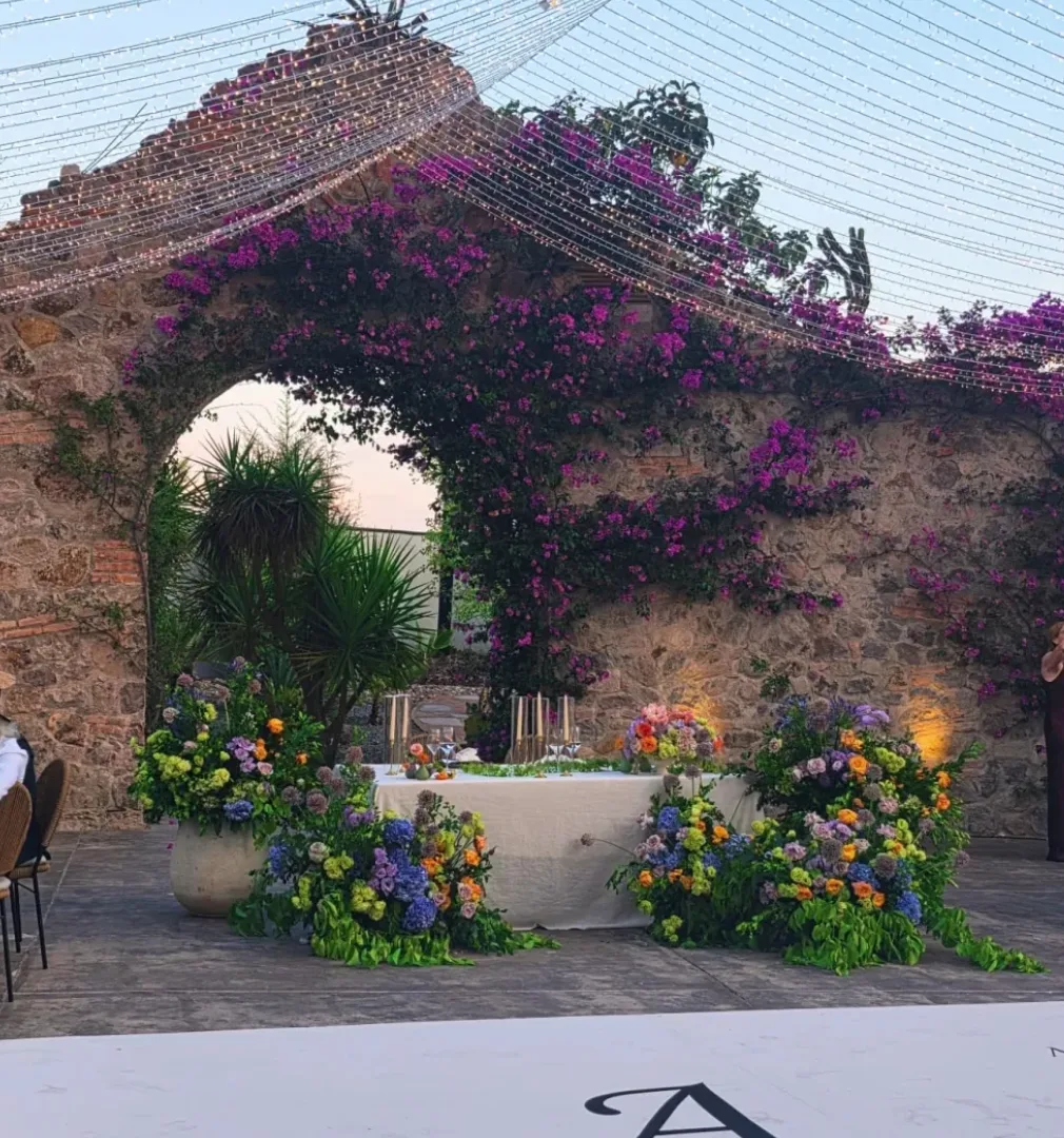 Colorful sweetheart table framed by stone arches and bougainvillea at Hacienda Agualuna