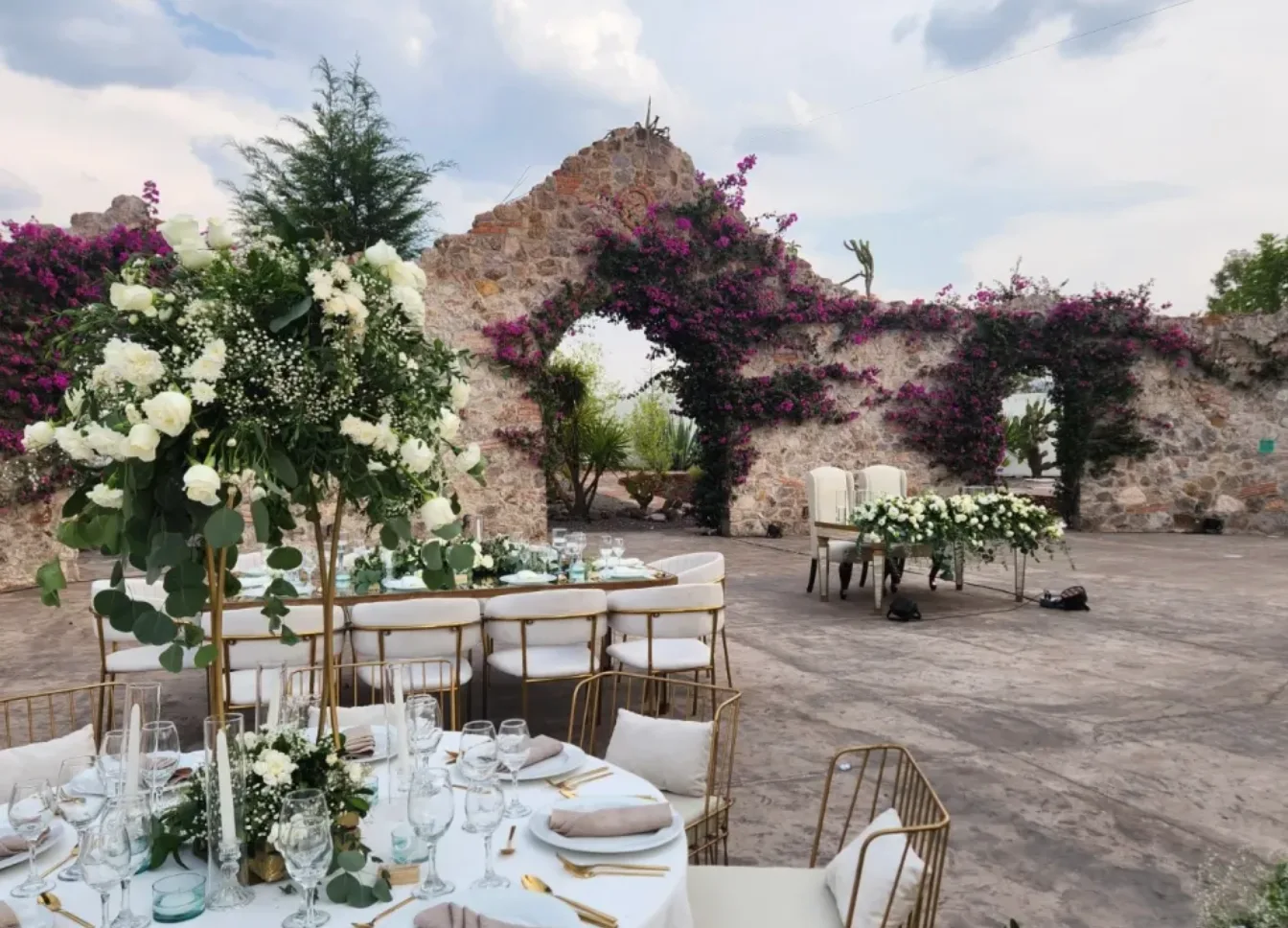 White-and-green outdoor reception setup in Hacienda Agualuna's stone-arch courtyard