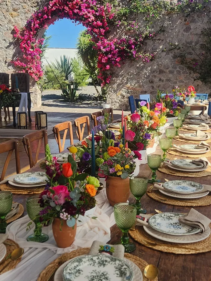 Colorful wedding tablescape beside a bougainvillea-covered arch at Hacienda Agualuna
