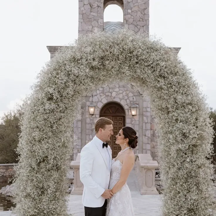 Newlyweds beneath a floral arch in front of the private chapel