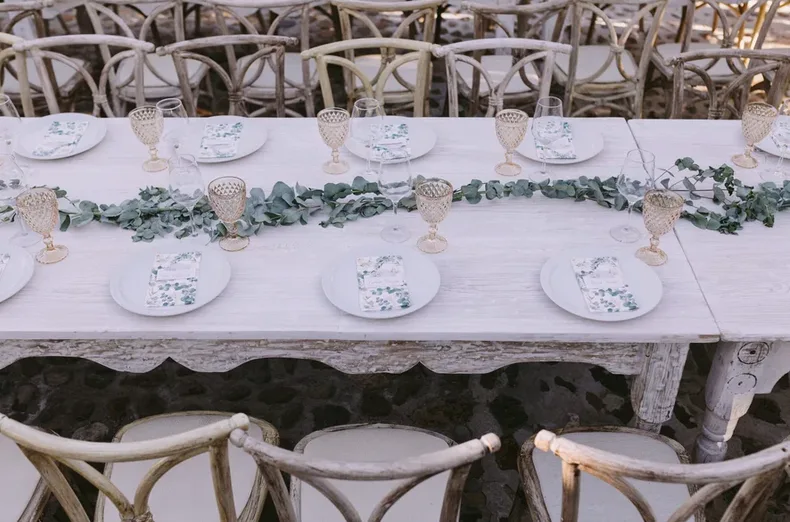 Rustic wedding table set with white place settings and greenery